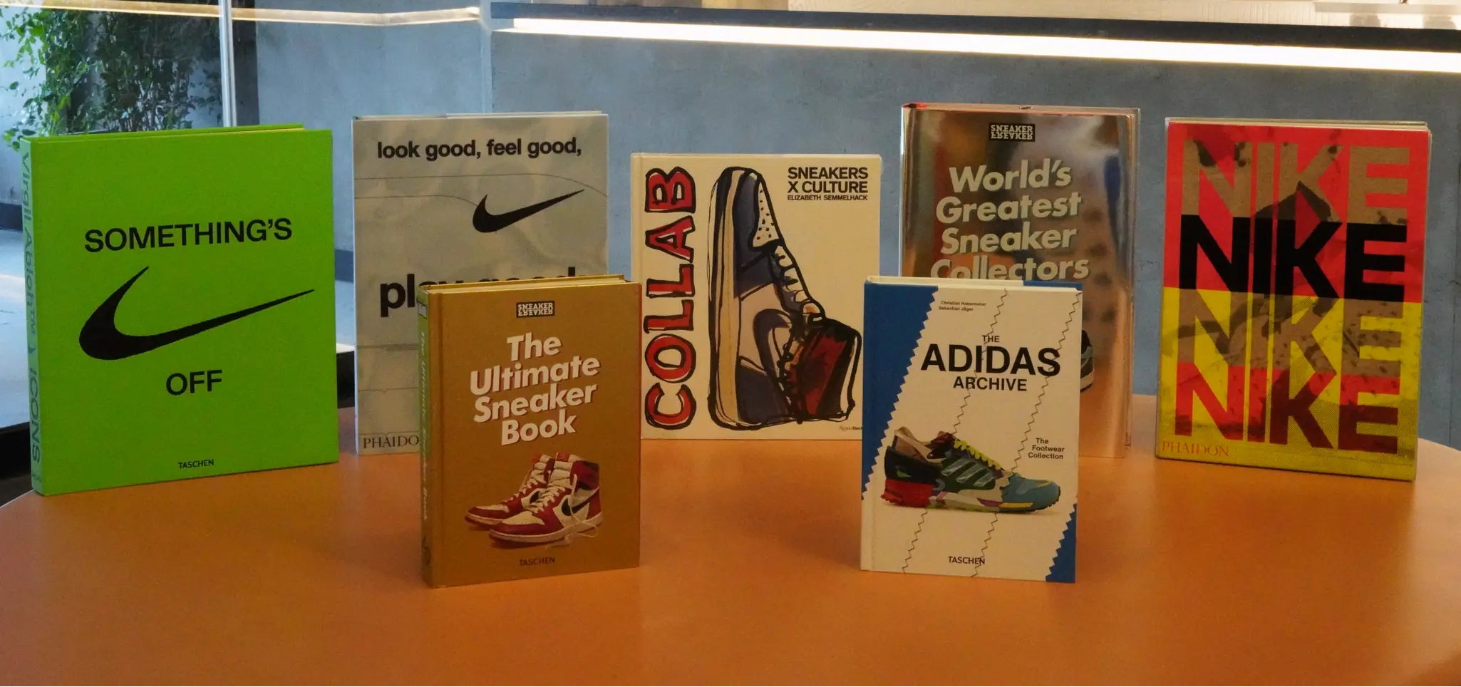 Collection of books related to sneaker culture on a table with a modern interior background